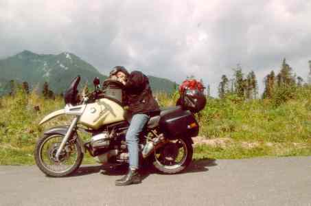 BMW R1100GS, with Ernst on it, holding a camera; mountains in the background