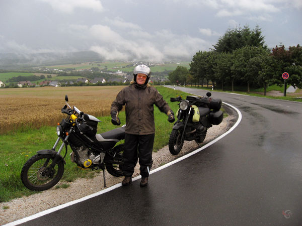 Sylvia in rain clothing and two motorcycles